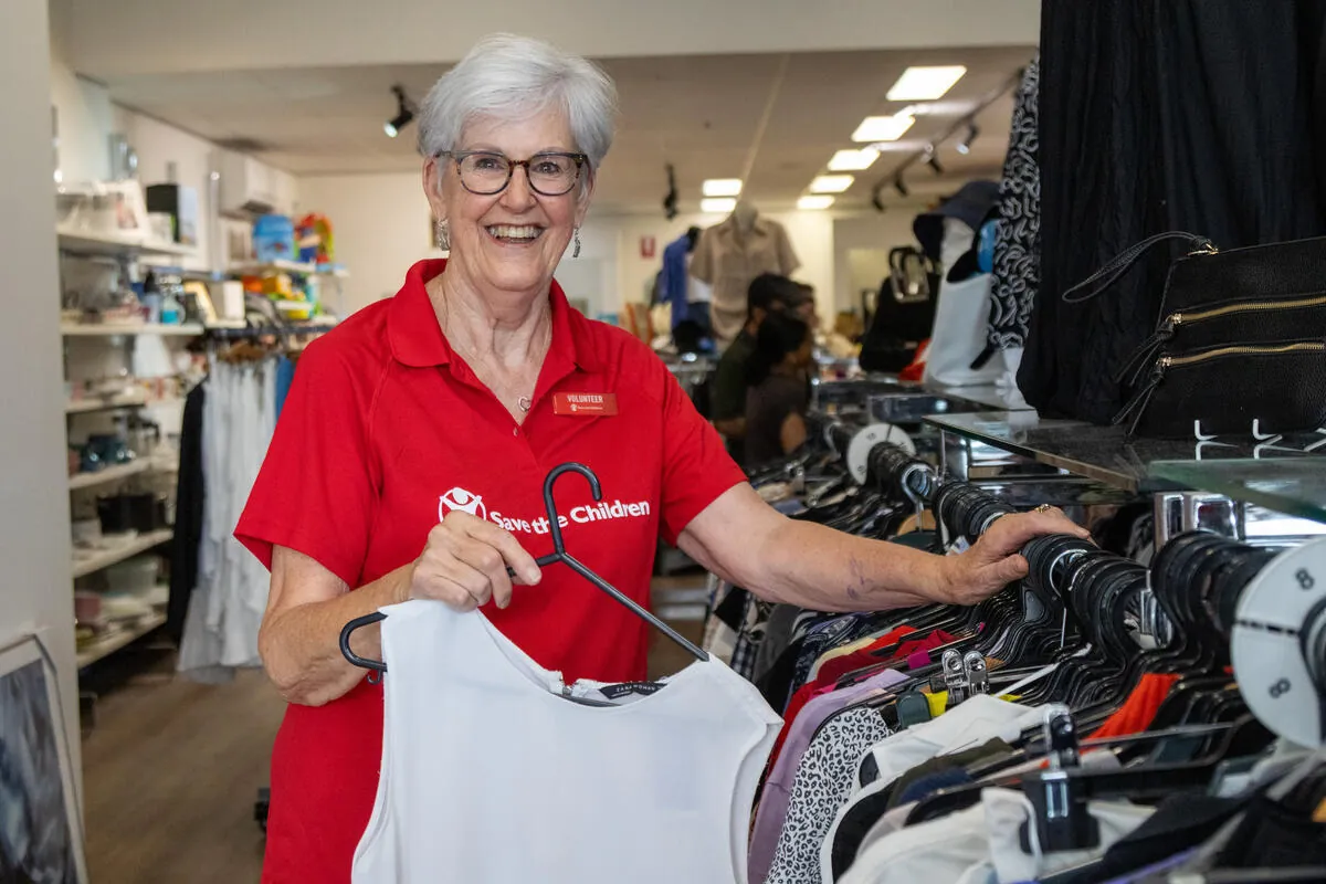 Op shop volunteer Marg sorts clothing on a rack