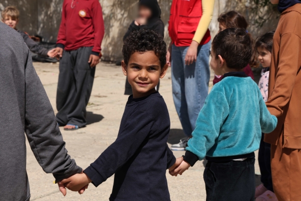 5 year old Imad holds hands with other children at a Child Friendly Space in Lebanon